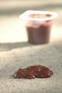 A glob of dark chocolate pudding is used to simulate dark, tarry stool.