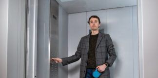 Handsome stylish man standing with labrador dog in elevator