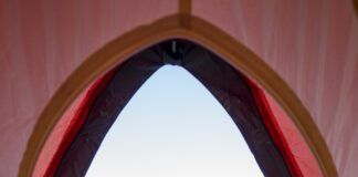 Dog sitting outside pitched tent with Tent Seebensee in background