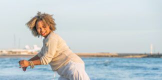 Woman playing with her dog on the beach while the dog bites her pants