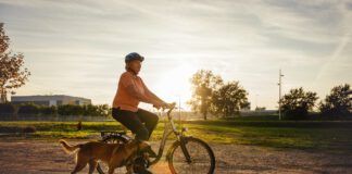 Senior woman riding bicycle and walking Malinois dog