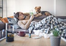 Woman lying sick on sofa with her dog