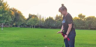 A white dog on a leash looks intently at its owner for hand commands.