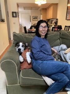 A dog relaxes with a dog sitter during a stay over at her home.