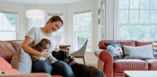 A woman introducing a cat to a dog, the cat is clearly upset.